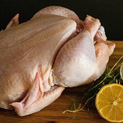 A whole raw chicken on a wooden board